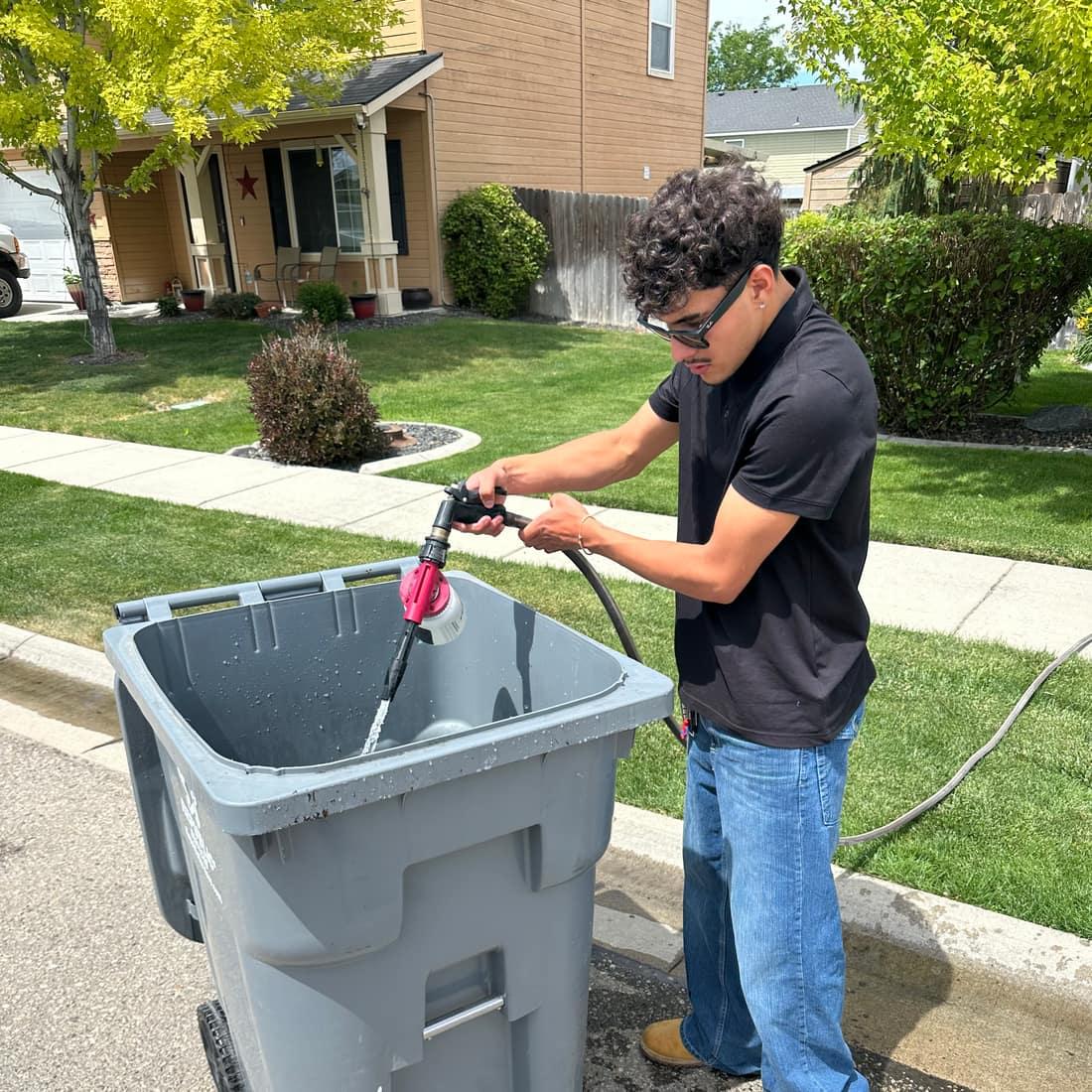 Bin Barber rinsing a trash bin at the curb