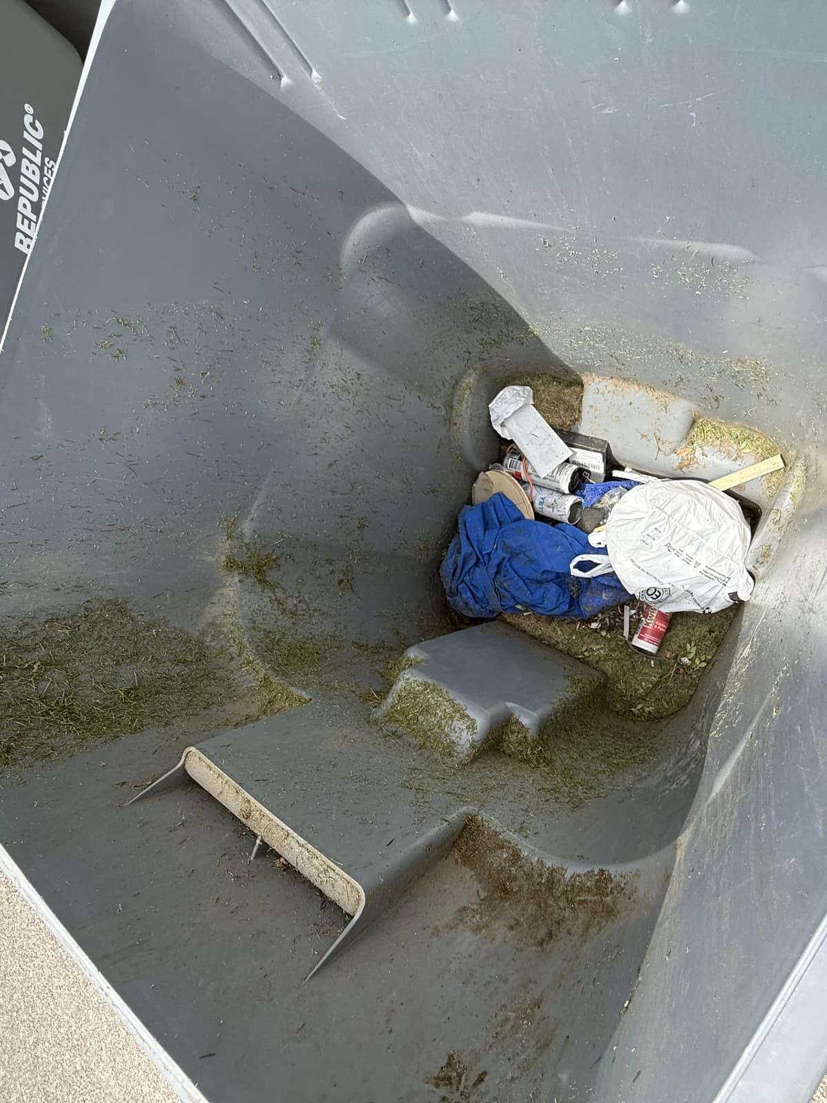 Inside of a dirty trash bin with caked grime and debris before cleaning